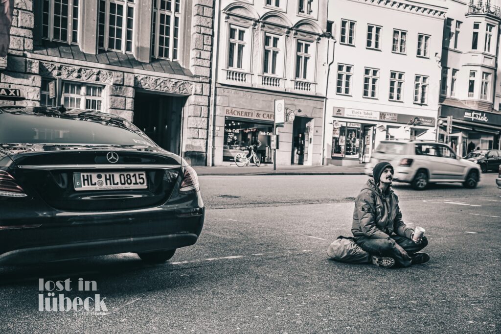 Beckergrube Lübeck Bettler vs. Mercedes Blick auf Bäckerei